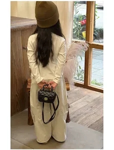 Girl's mini black quilted crossbody bag with gold lock shown on child model back