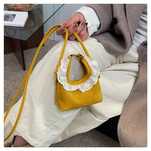 Détail macro du mini sac jaune montrant la dentelle blanche et la broderie ajourée