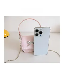 Pink checkered mini bag with lace trim and bow shown next to a phone for size comparison