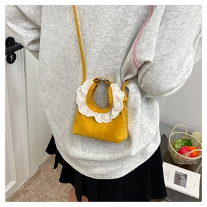 Détail d'un mini sac à main jaune avec dentelle et bandoulière porté par un mannequin