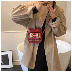Detail of red plaid crossbody bag with bow and cartoon puppy on khaki trench coat