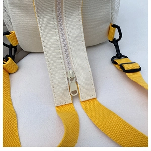 Détail du sac en toile blanche pour enfant avec sangle jaune et crochet en plastique noir
