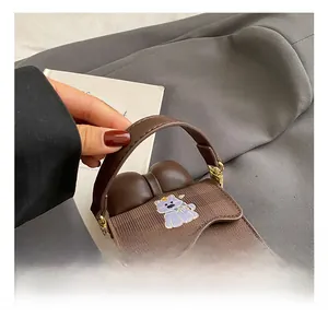 Détail du sac bandoulière marron à carreaux avec broderie dessin animé et chaîne dorée