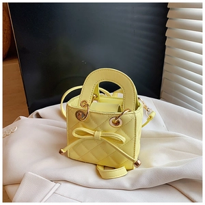 Detail of yellow quilted mini bag featuring leather bow and golden hardware on a blazer