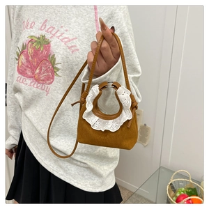Détail du mini sac à main en daim marron avec bordure en dentelle blanche sur l'anse