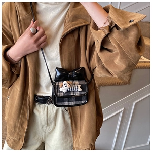 Detail of plaid mini crossbody bag with black bow and cartoon dog charm on child