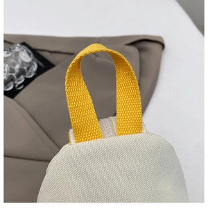 Détail du sac en toile avec poignée en sangle jaune vif et fermeture éclair