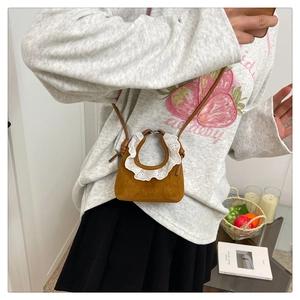Détail du mini sac en daim marron avec bordure en dentelle blanche et fine bandoulière