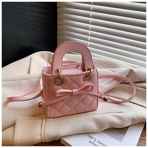 Detailed view of pink quilted mini handbag with bow detail on beige blazer background