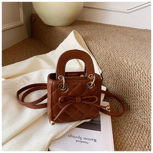 Detailed macro view of brown quilted mini handbag with a cute bow and gold hardware