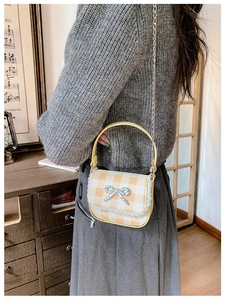 Child wearing yellow plaid crossbody bag with silver bow and lace trim detail