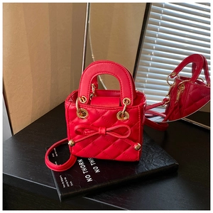 Detail view of red quilted mini handbag with bow decoration and gold metal hardware