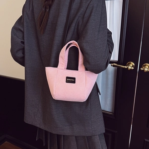 Sac seau en velours côtelé rose pour enfants porté par un mannequin en intérieur