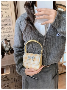 Detail of yellow plaid mini handbag with white lace trim and silver metal bow decoration