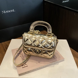 Detail of golden mini quilted handbag with diamond stitching and metal turn-lock