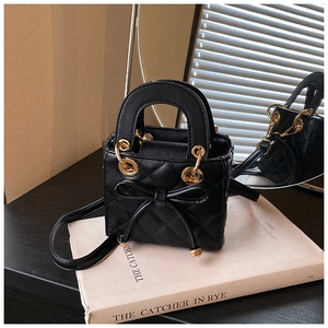 Close-up of black quilted mini bag with bow detail and gold circular handle