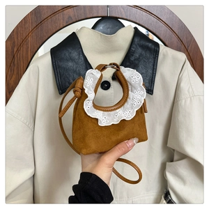 Gros plan du mini sac à main en daim marron caramel avec bordure en dentelle blanche brodée