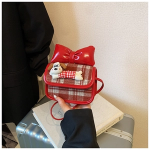 Detail of kids red plaid shoulder bag featuring a cartoon dog and large bow accent