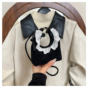 Détail d'un mini sac à main noir avec dentelle blanche et fine bandoulière en cuir