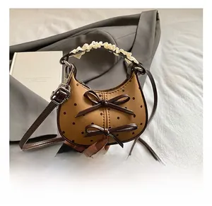Close-up of brown polka dot kids bag with bows and lace handle on grey suit