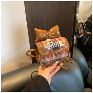 Detail of children dog crossbody bag with red plaid flap and a large brown bow
