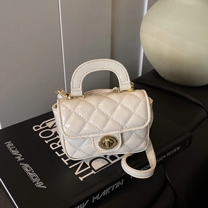 Close-up of quilted mini handbag with gold twist lock on black decorative books