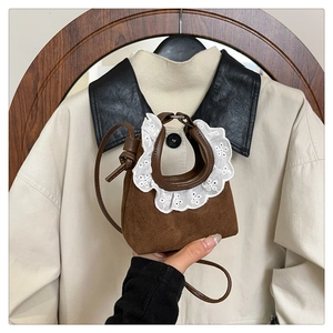Détail du mini sac en daim marron avec broderie de dentelle blanche et sangle