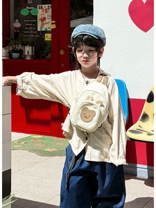 Enfant portant un sac bandoulière en toile beige avec un motif d'ours mignon en ville