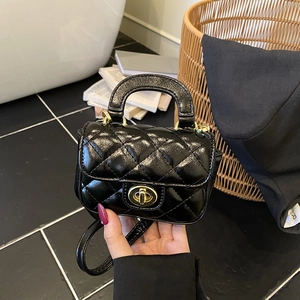 Detail of a mini black quilted lacquer purse featuring a gold circular twist lock