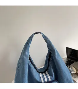 Detail of blue denim tote bag with triple white stripes and top zipper closure