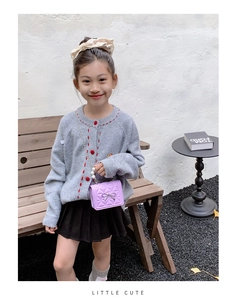 Détail d'un mini sac violet matelassé avec nœud argenté et chaîne de perles sur enfant