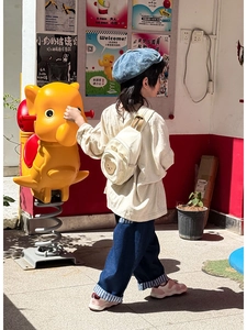 Détail de la broderie d'ours sur un sac à dos pour enfant en toile crème porté par un bébé