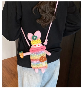 Detail of handmade crochet rabbit crossbody bag with rainbow outfit and carrot charm