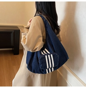 Detailed close-up of dark denim tote bag with white stripes and zipper pocket