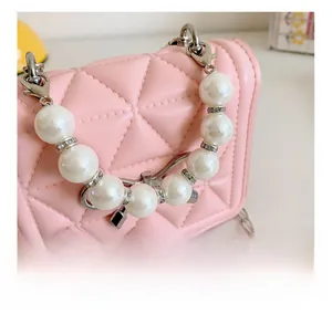Détail du mini sac rose matelassé pour enfant avec poignée en perles et chaîne en métal