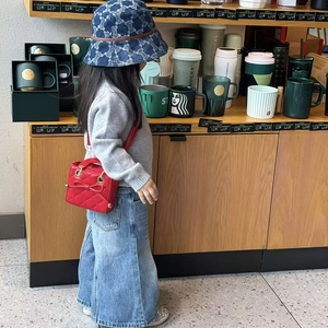 Red quilted mini crossbody bag with bow detail for kids styled with denim hat