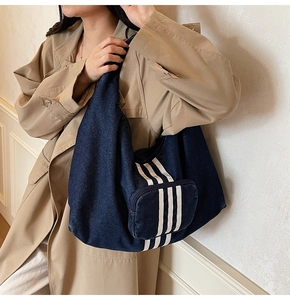 Detail of blue denim hobo tote bag with front zipper pocket and three white stripes