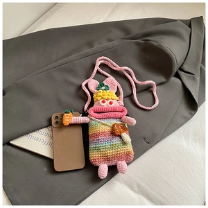 Close-up of handmade crochet monster bag with rainbow stripes and carrot accessory
