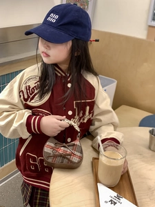 Dettaglio di una mini borsa a mano a quadri marroni con outfit in stile collegiale
