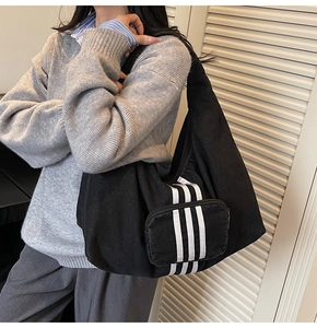 Detailed view of the large black denim tote bag featuring iconic triple vertical white stripes