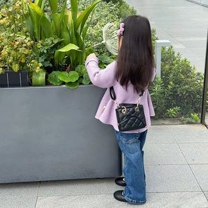 Toddler girl wearing black quilted mini handbag with bow detail and gold hardware