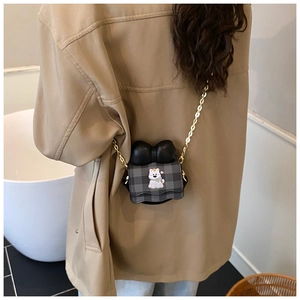 Fille portant un mini sac à carreaux avec nœud noir et motif de chiot dessin animé