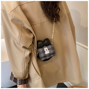 Détail du sac bandoulière enfant à carreaux avec écusson chien et nœud noir