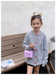 Détail d'un mini sac matelassé lilas avec nœud argenté et chaîne en perles sur un cardigan