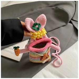 Macro shot of handmade crochet rabbit bag with rainbow stripes and 3D carrot detail
