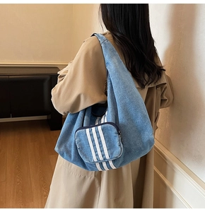 Detail of light blue denim tote with three white stripes and a matching mini pouch
