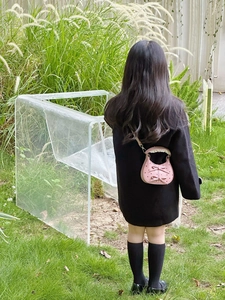 Pink mini children purse with bow details and lace handle worn by a girl in a garden