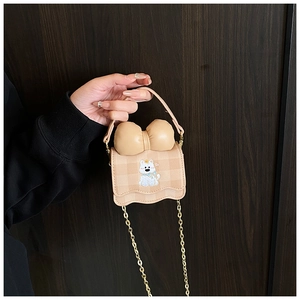 Détail du mini sac à bandoulière beige avec motif chiot dessin animé et nœud