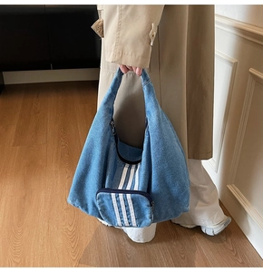 Detail view of large denim tote bag featuring three vertical stripes and front zipper pocket