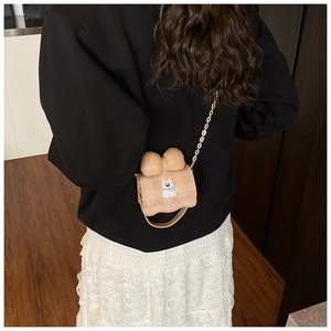 Détail d'un petit sac bandoulière chiot avec nœud porté sur une tenue noir et blanc